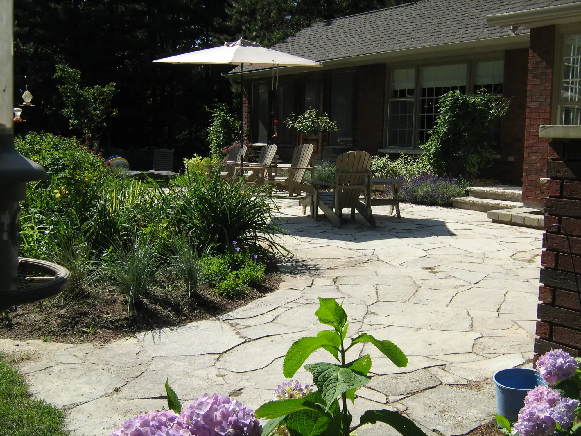 A finished backyard oasis with a drylaid flagstone patio surrounded by gardens